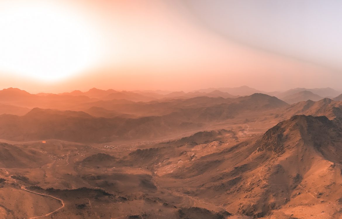 Panoramic view of a mountainous landscape during sunset with warm colors and shadows.