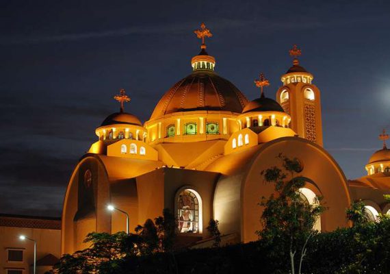 A church building with a large dome and multiple smaller domes, illuminated at night with decorative lighting.