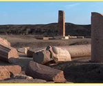 Ruins of ancient Egyptian columns and statues scattered across an archaeological site.