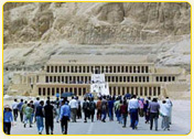 Visitors approaching the grand entrance of the Temple of Hatshepsut in Luxor, Egypt, surrounded by rocky cliffs.