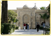 Facade of a historic building with intricate architectural details and people walking in front of it.