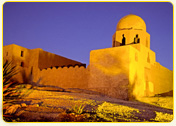 Historic structure with a dome and two figures silhouetted against a twilight sky in Egypt.
