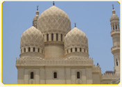 Architectural detail of a building with multiple domes and intricate designs in a light-colored stone.
