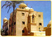 Historic building with domed roofs and a palm tree in front, showcasing traditional architecture in Egypt.
