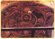 Fresco depicting Christ Pantocrator surrounded by celestial symbols in a historical church.